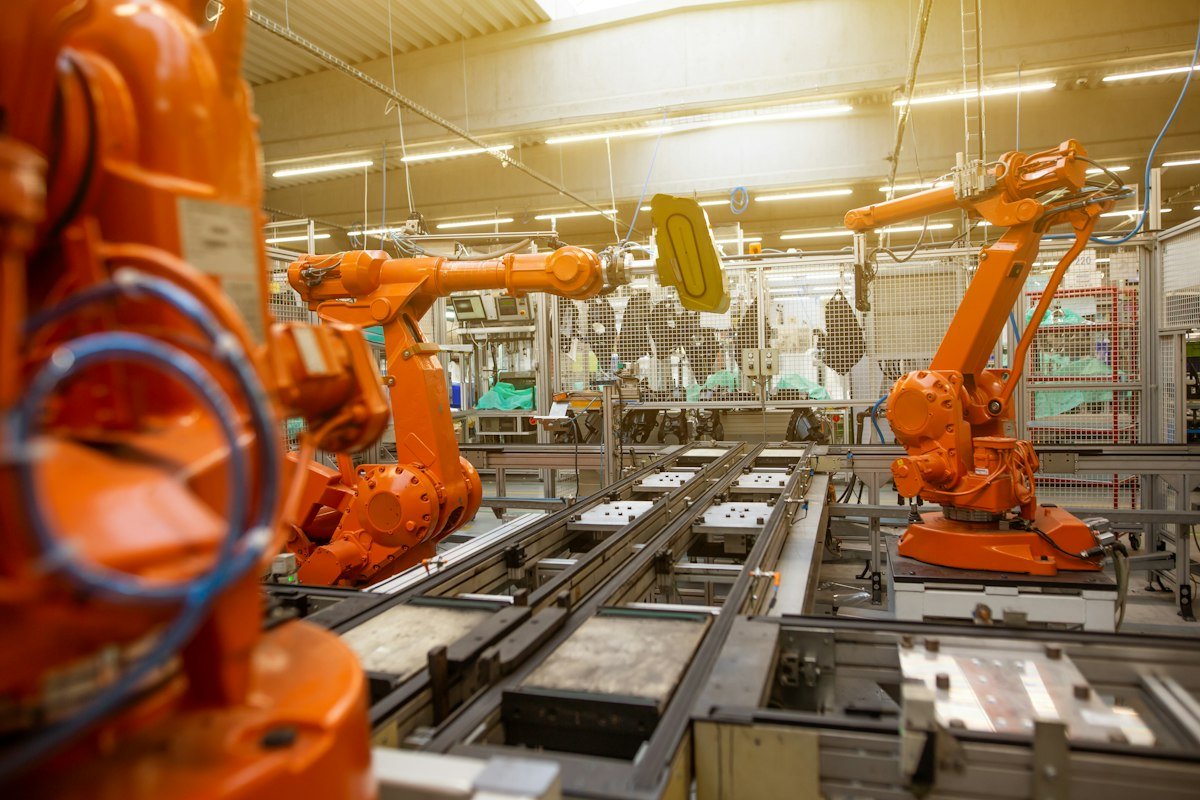 Orange industrial robots working on an automated production line.