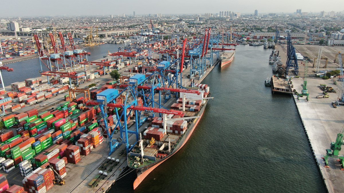 Container terminal with cranes and cargo ships at the quayside.